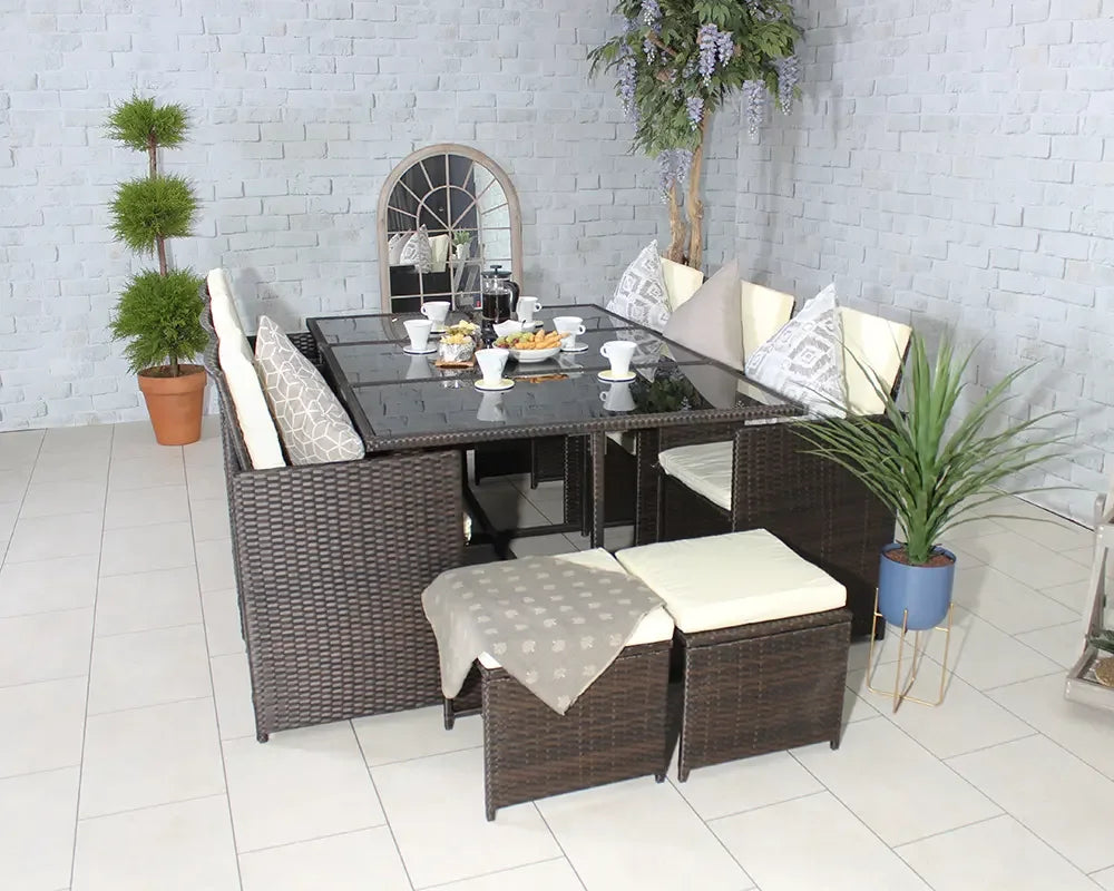 Brown rattan dining set with cream cushions and glass table, arranged with breakfast setting indoors