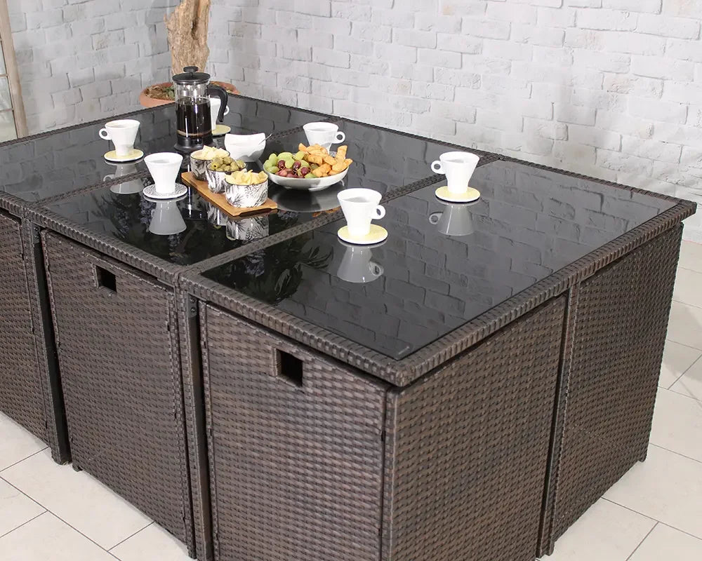 Brown rattan garden dining set with glass table top, coffee cups and snacks arranged on top