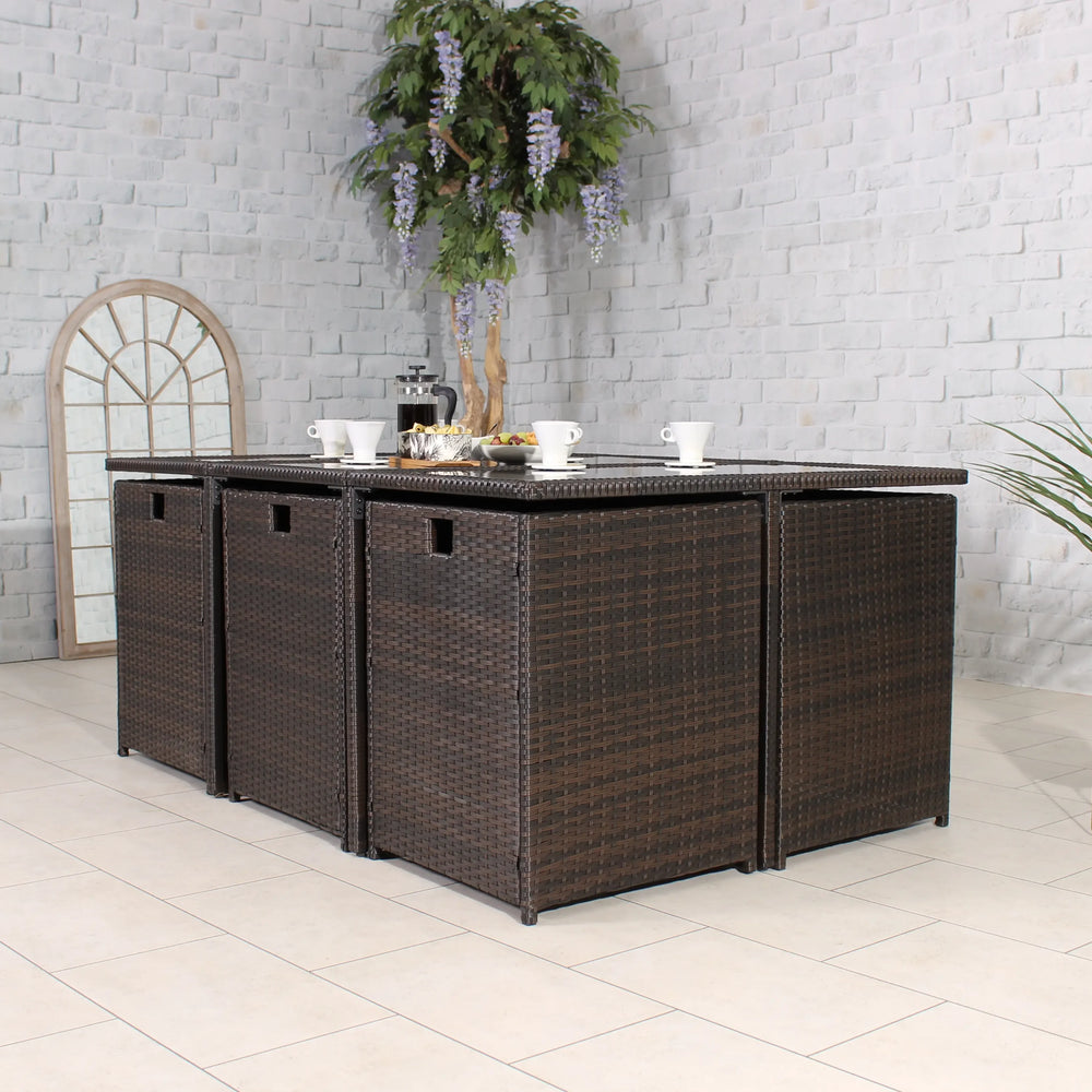 Brown rattan garden dining set with four cube seats and table, set for breakfast indoors
