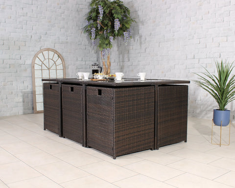 Brown rattan garden dining set with four cube seats and table, set for breakfast indoors
