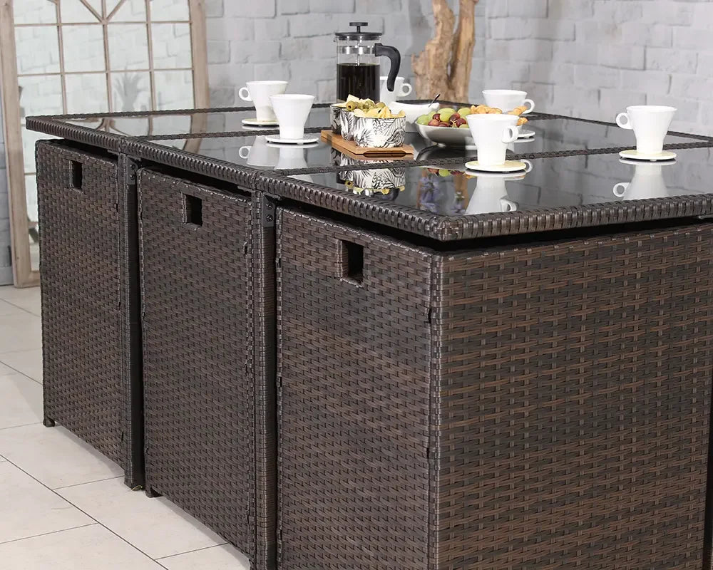 Brown rattan garden dining table set with glass top and breakfast items displayed