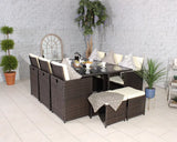 Brown rattan dining set with glass table, cream cushions, and stools in a tiled room
