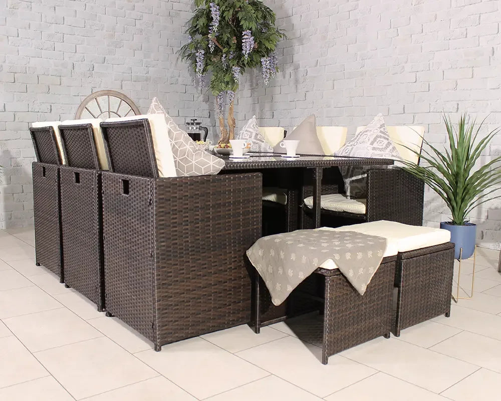 Brown rattan garden dining set with cream cushions and glass table, arranged indoors