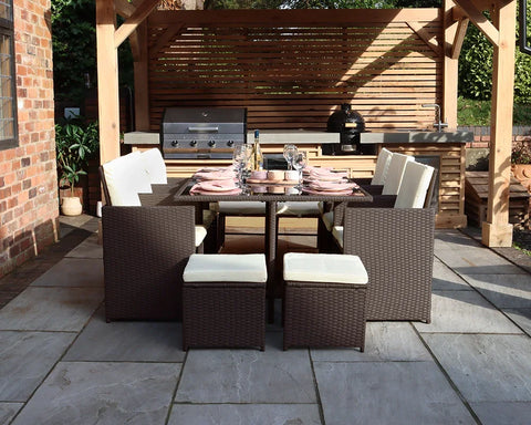 Brown rattan garden dining set with cream cushions arranged under wooden pergola