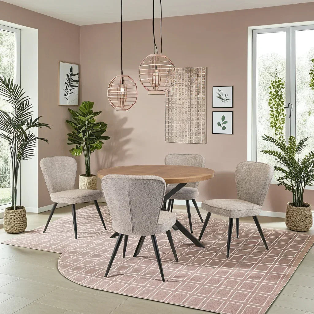 Round wooden dining table with four upholstered chairs on patterned rug in modern dining room