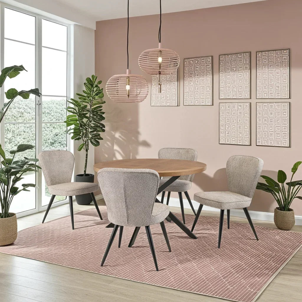 Round wooden dining table with four beige upholstered chairs on a pink rug