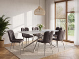 A modern dining set featuring a white rectangular table with a sculptural metal base and six tufted gray upholstered chairs, styled in a bright, contemporary dining room.