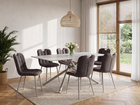 A modern dining set featuring a white rectangular table with a sculptural metal base and six tufted gray upholstered chairs, styled in a bright, contemporary dining room.