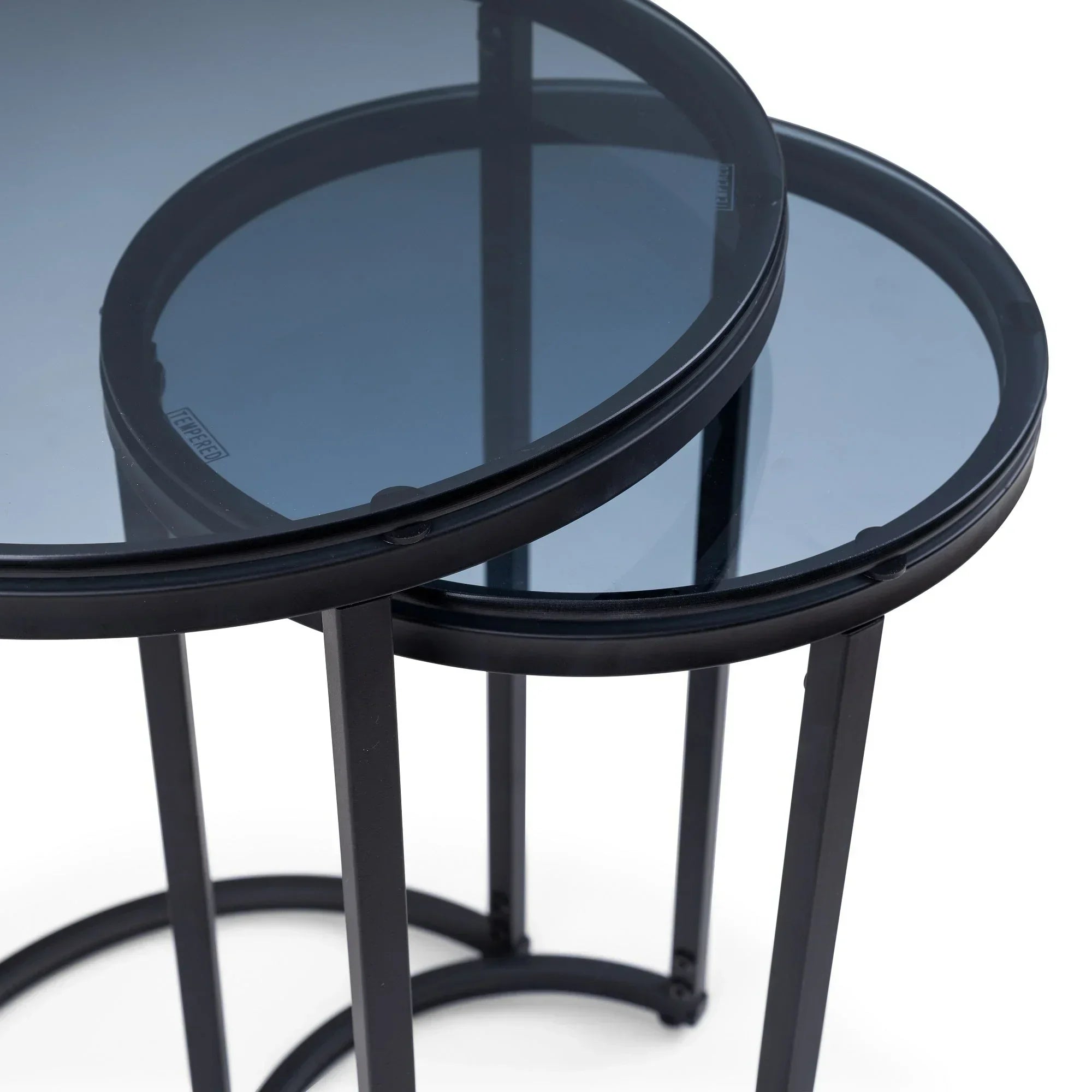 Round nesting side tables with black metal frames and smoked glass tops, close-up view