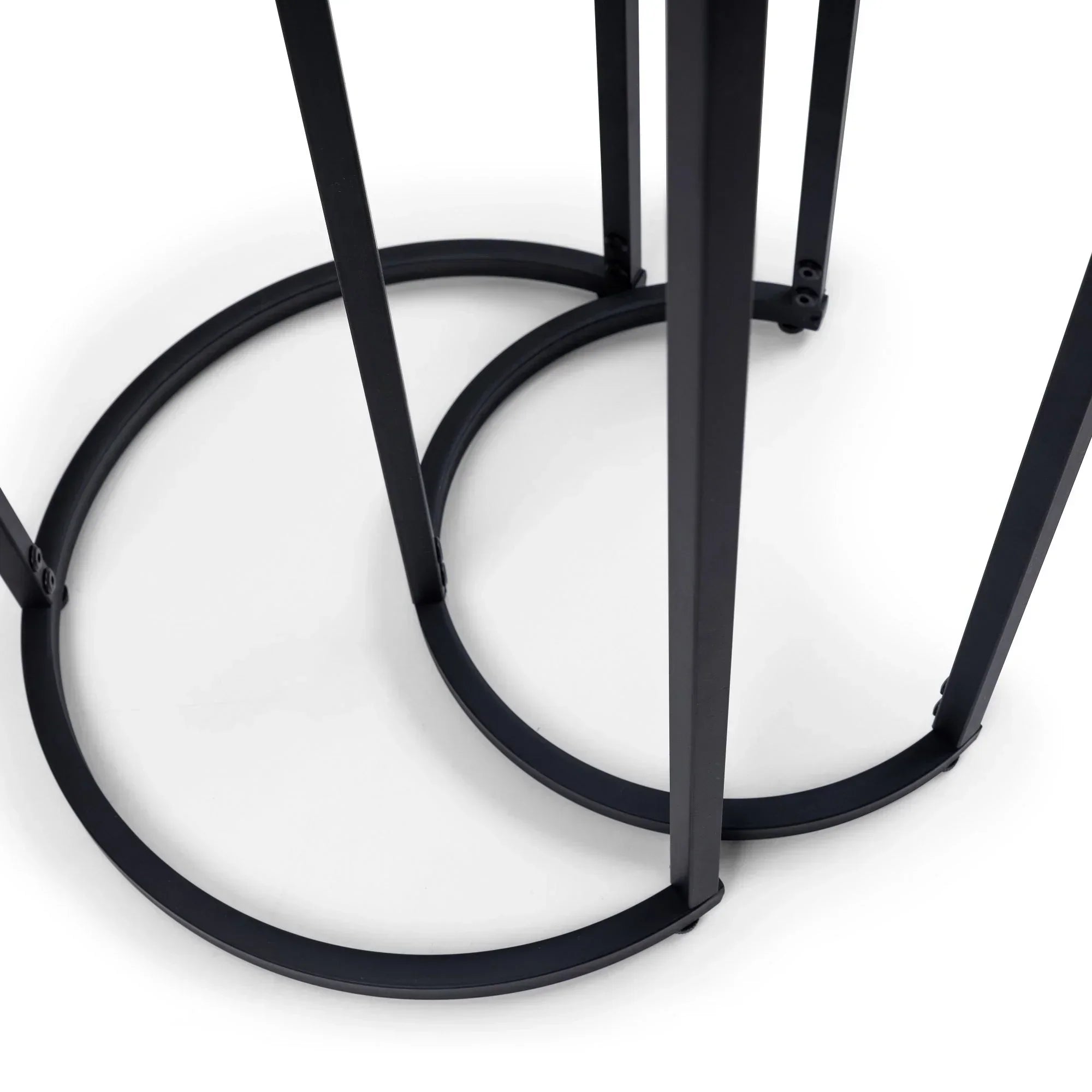 Close-up black metal base of round nesting side tables showing overlapping semicircle legs