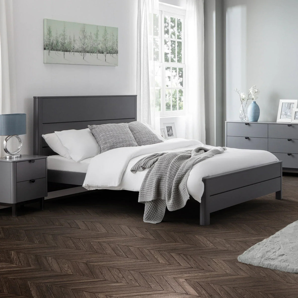 Grey double bed with white bedding and grey throw in a modern bedroom setting