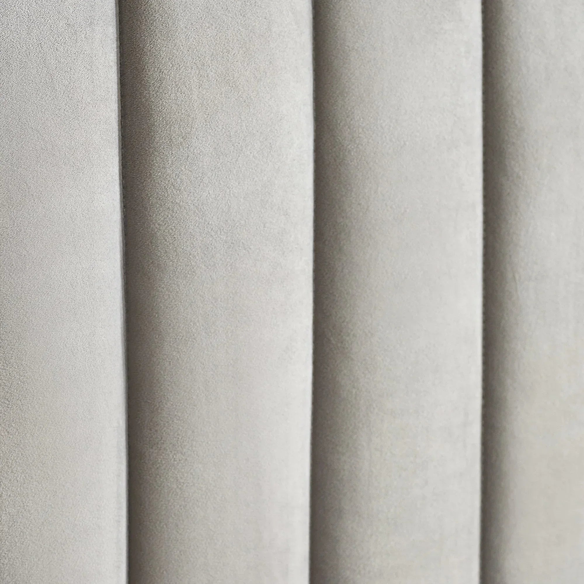 Close-up of grey upholstered bed headboard with vertical panel detailing