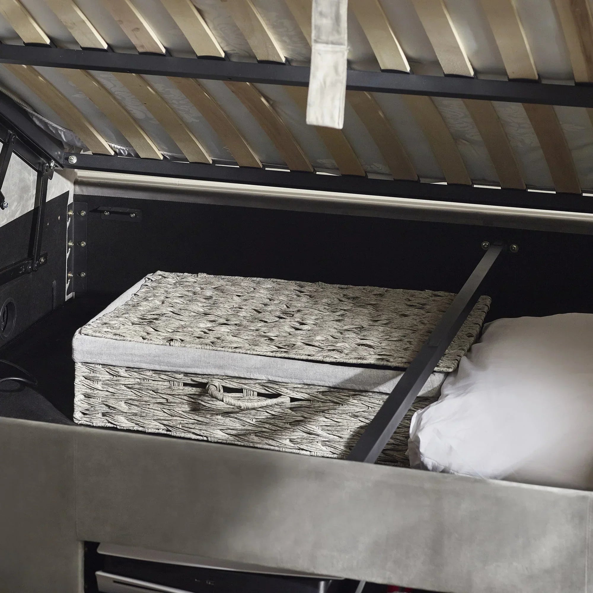 Lift up ottoman bed storage space with wicker basket and pillow inside base compartment