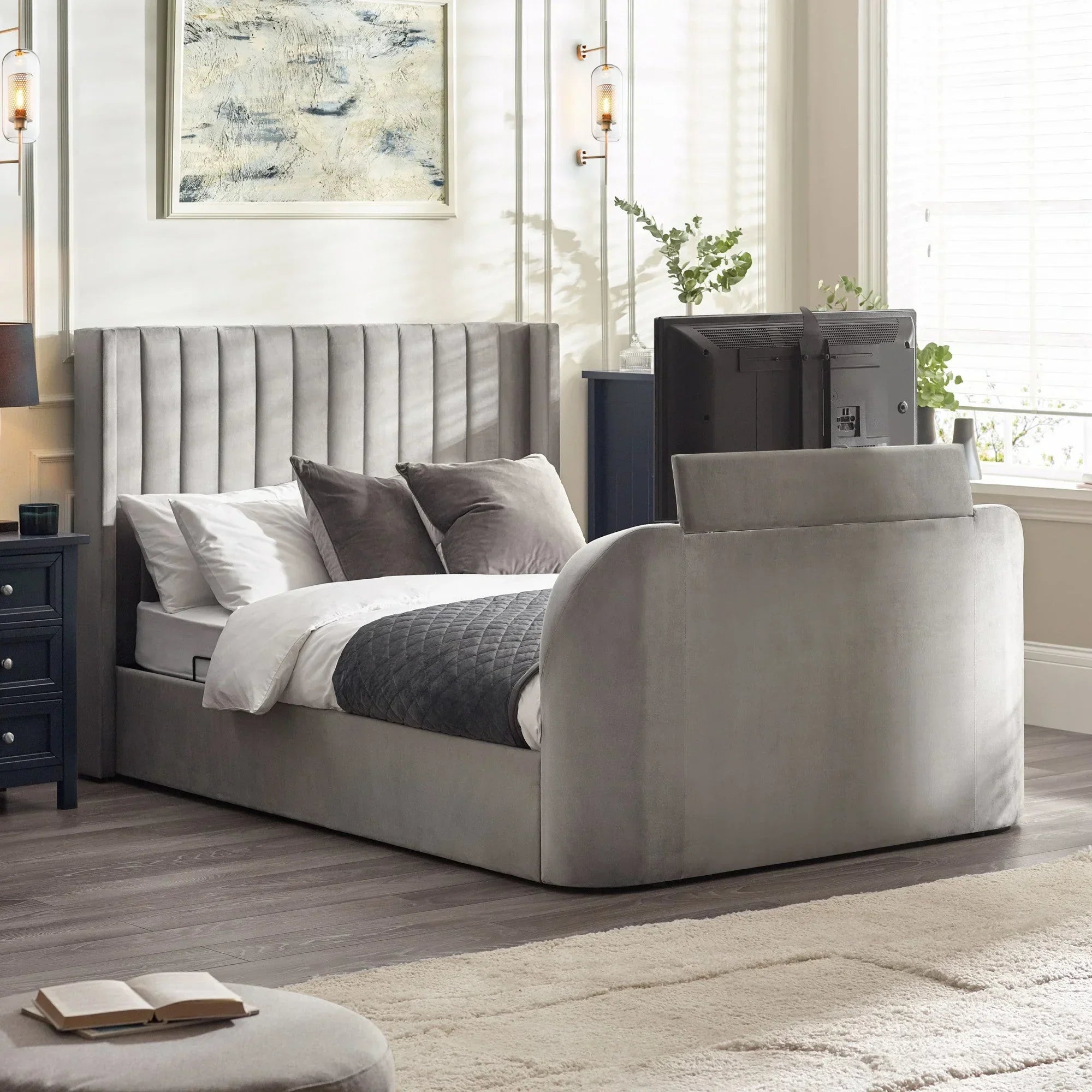 Silver upholstered bed with padded headboard and built-in TV at foot in modern bedroom