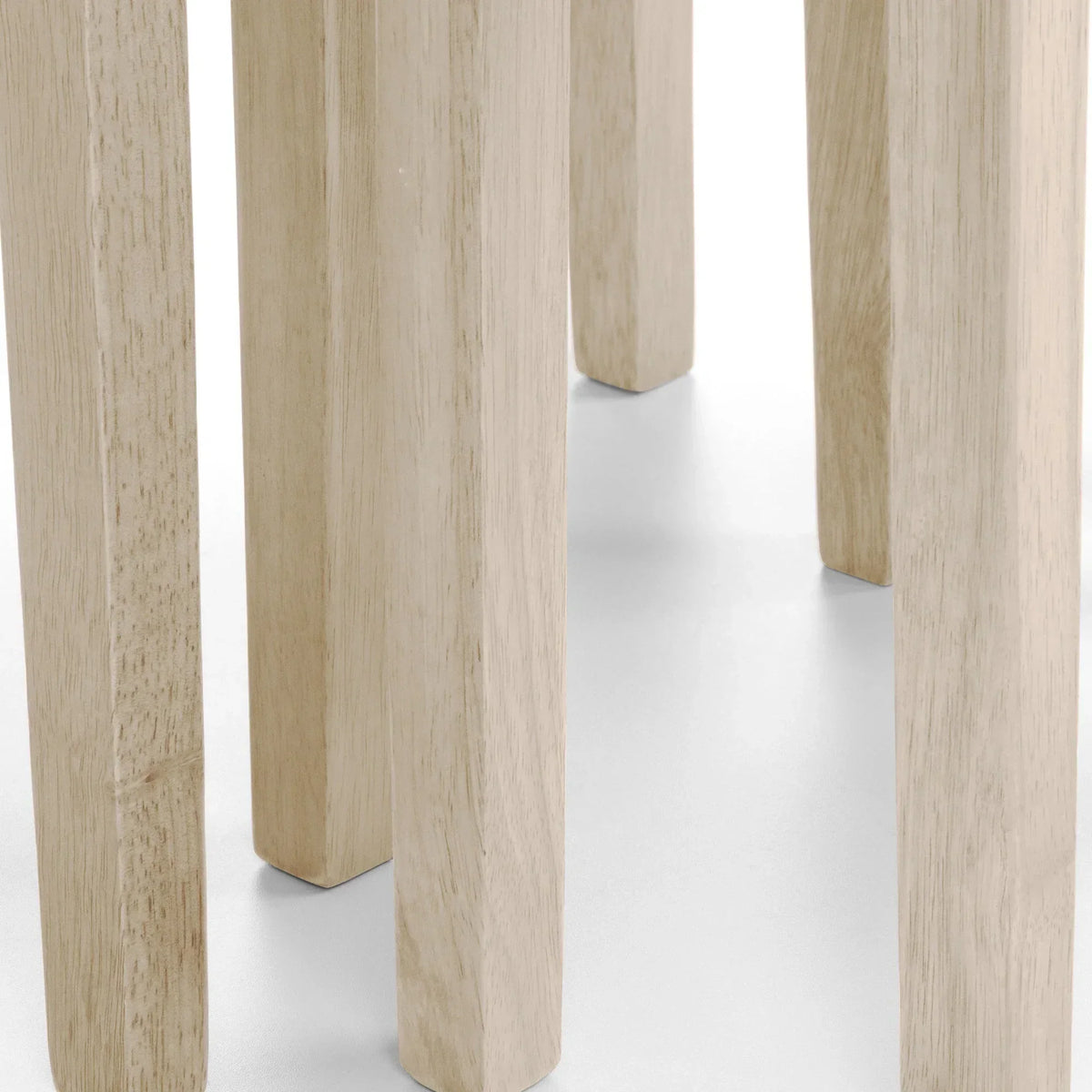 Close-up of solid wood dining table legs in natural finish on white background