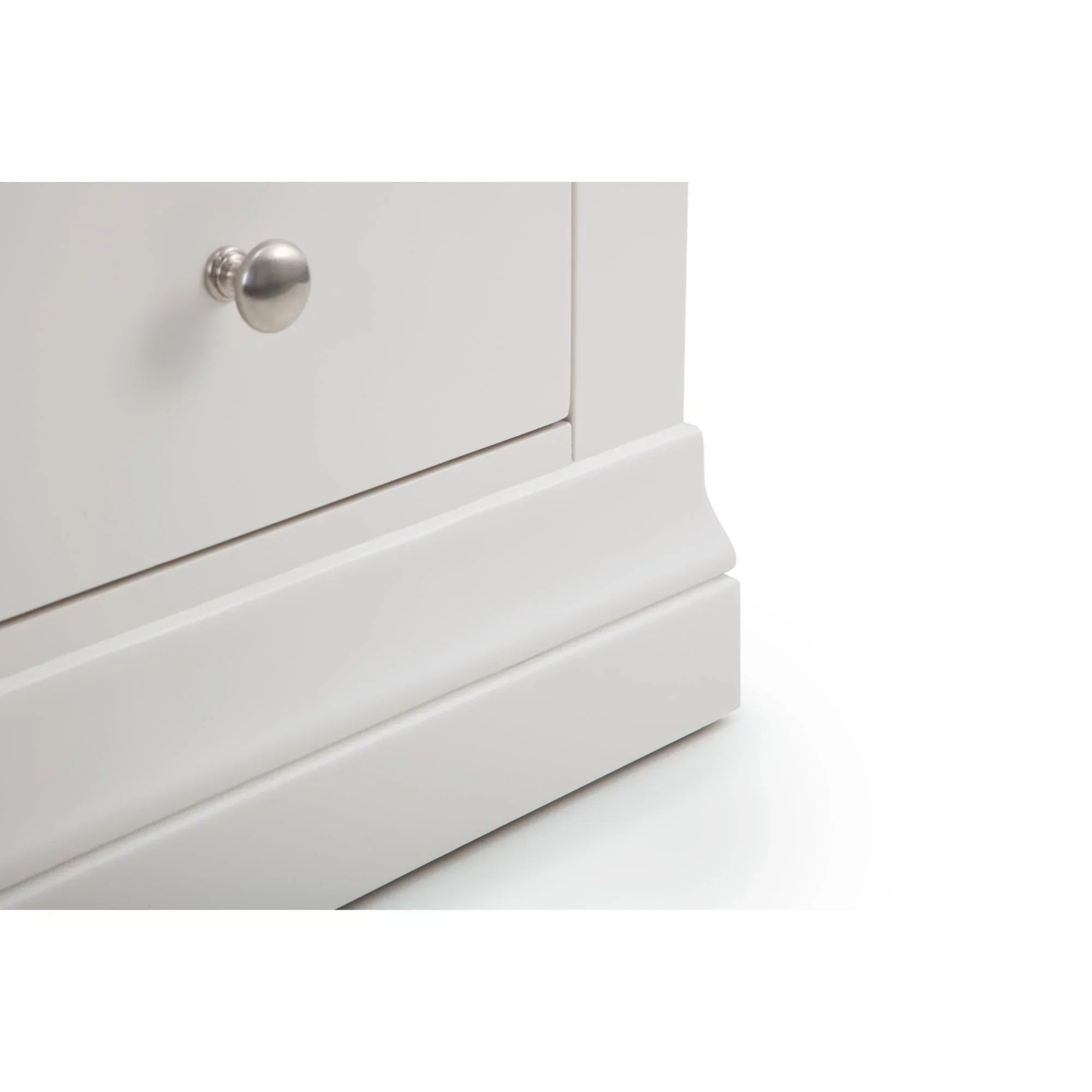 Closeup of surf white chest drawer corner with silver knob and plinth base detail