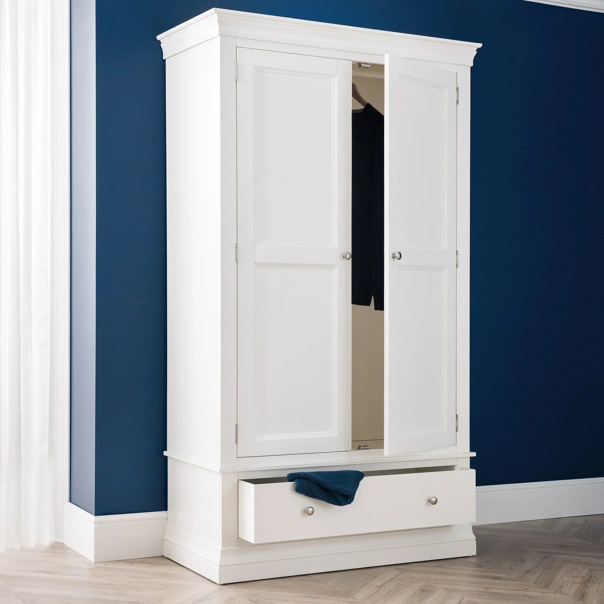 Surf white wardrobe with panelled doors and open drawer in a modern bedroom corner