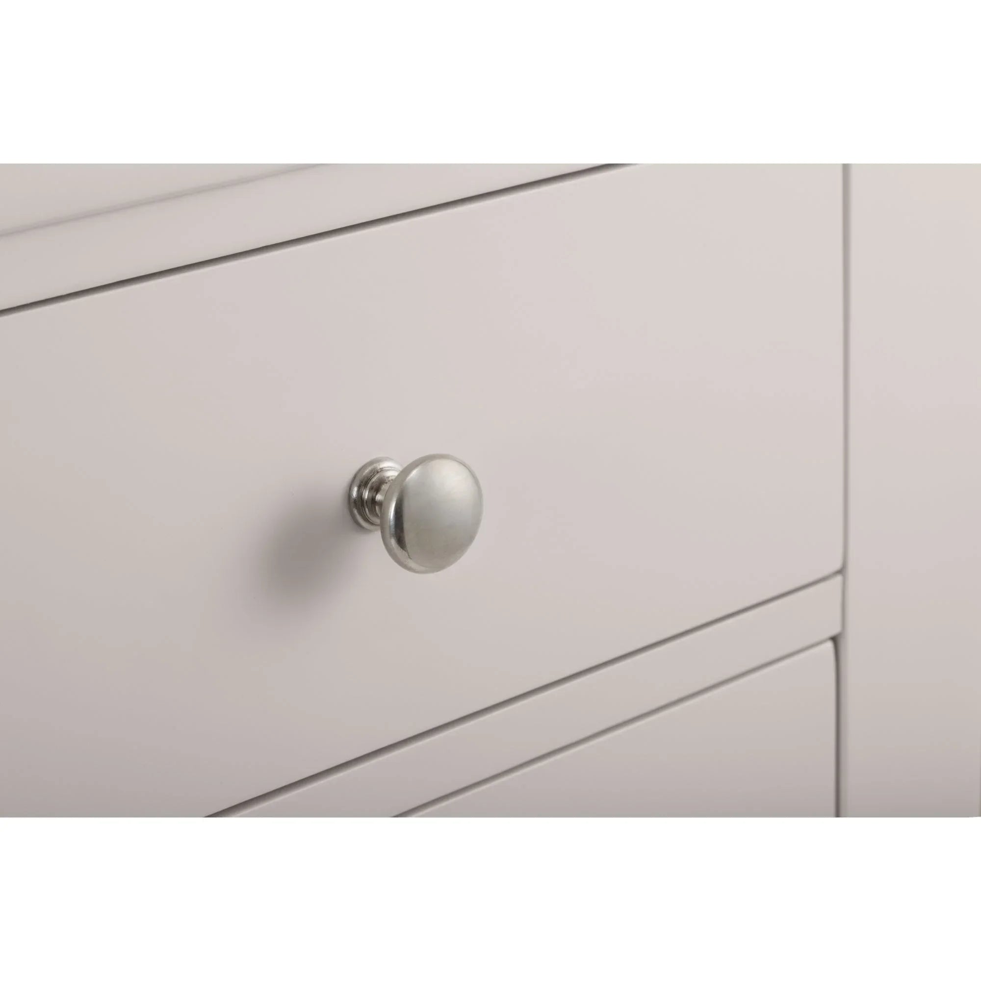 Light grey chest of drawers close-up showing round metal drawer handle and smooth finish