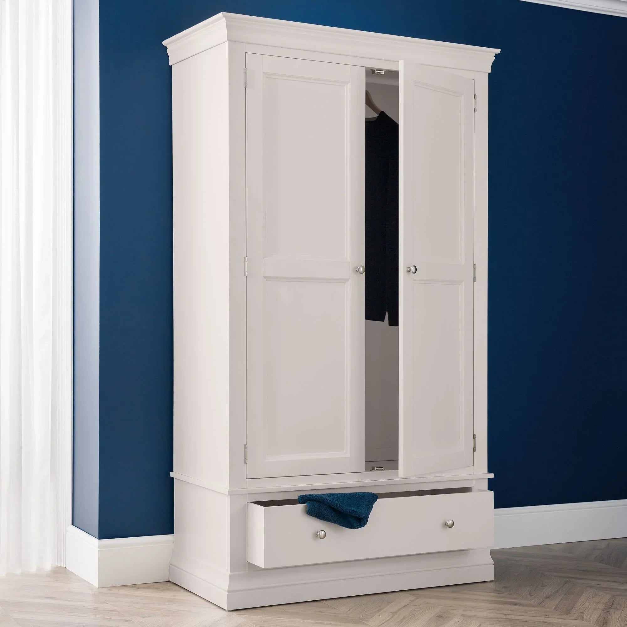 Light grey wardrobe with double doors and lower drawer in modern bedroom setting