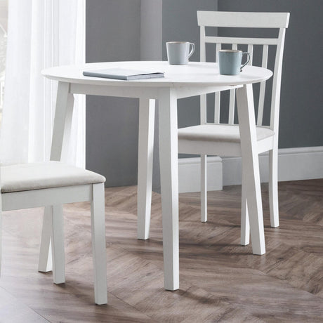 White round Coast dropleaf table with one leaf dropped, two white chairs, wood floor, grey walls
