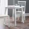 White round Coast dropleaf table with one leaf dropped, two white chairs, wood floor, grey walls