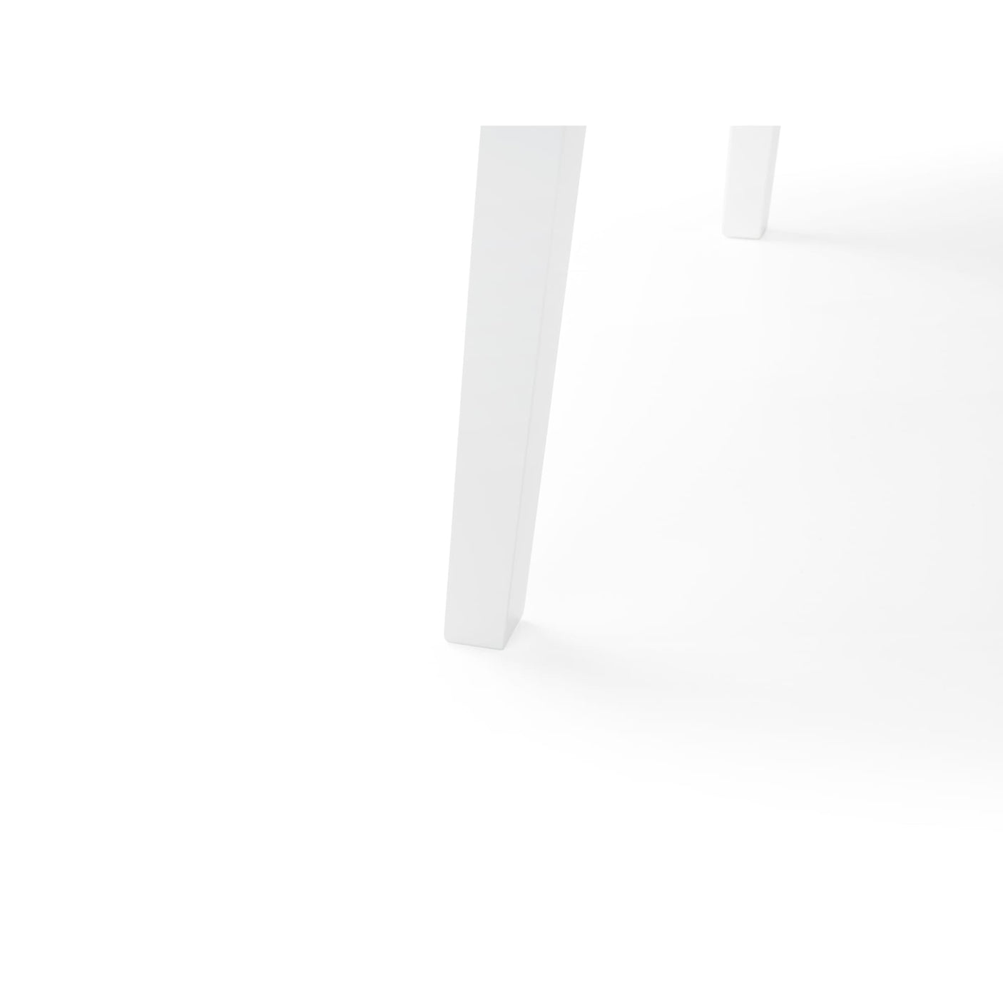 Close-up of white table tapered legs and rounded edge on white background.