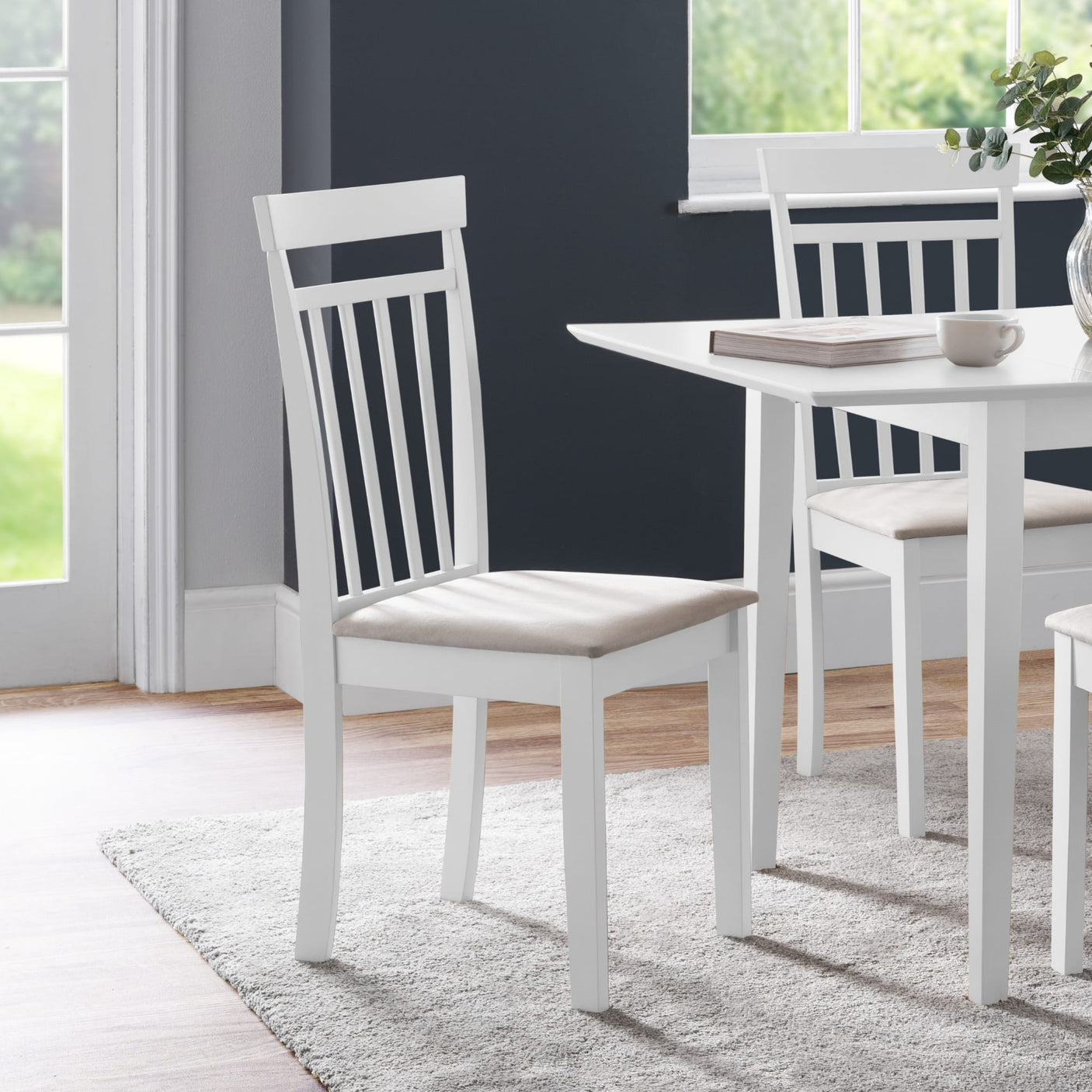 White wooden dining chair with beige cushioned seat angled left in modern dining room