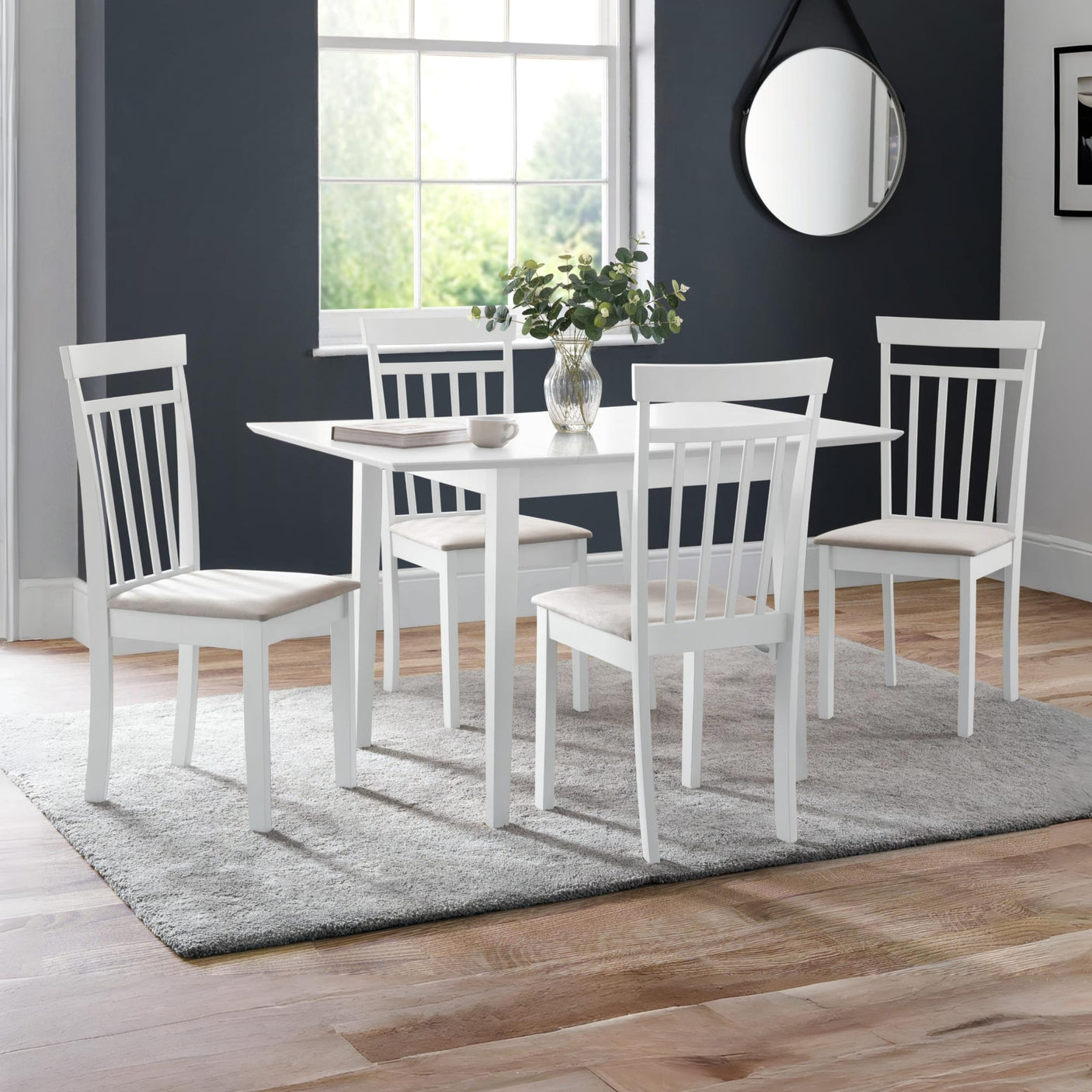 Set of four white wooden dining chairs with beige seats around white table in bright room