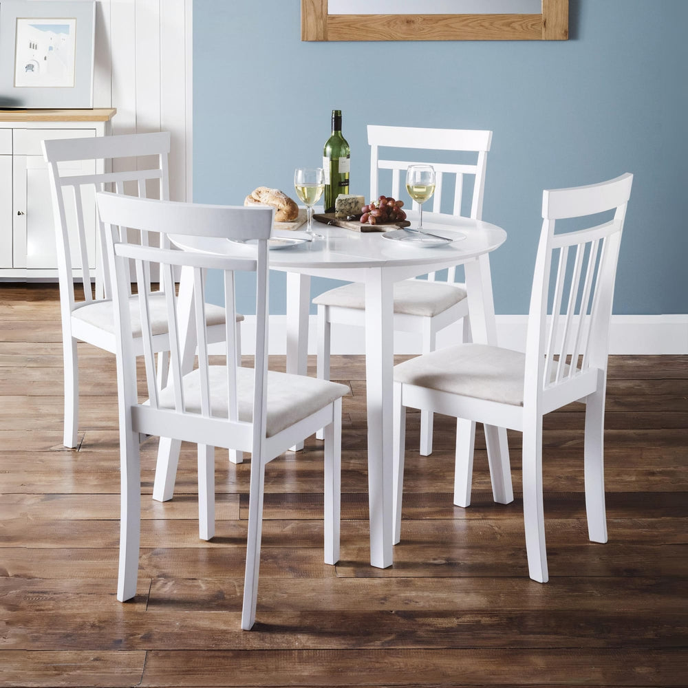 Set of four white wooden dining chairs with vertical slats and cushioned seats around a white round table