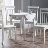 White wooden dining table with one leaf down and four matching chairs in room