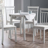 White wooden dining table with one leaf down and four matching chairs in room