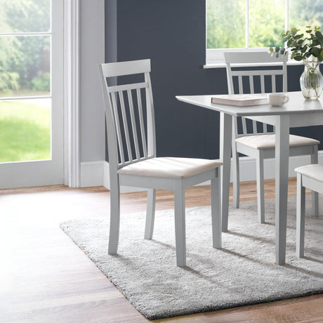 Light grey wooden dining chairs with vertical slats and cream cushioned seats near white table