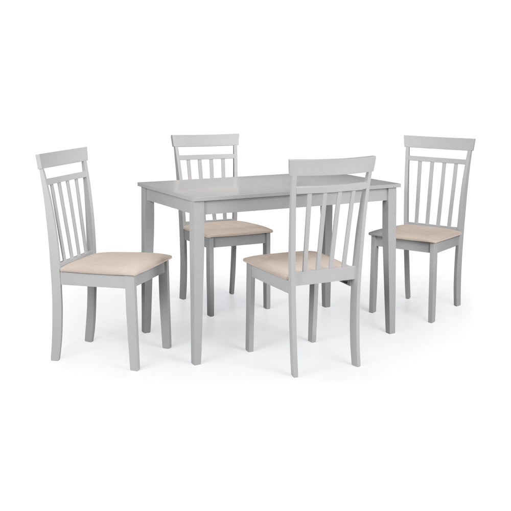 Two white dining chairs with beige seats shown beside round white dining table near window over wood flooring.