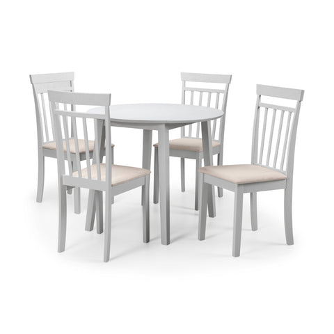 Set of four white dining chairs with beige seats around pale round dining table on white background.