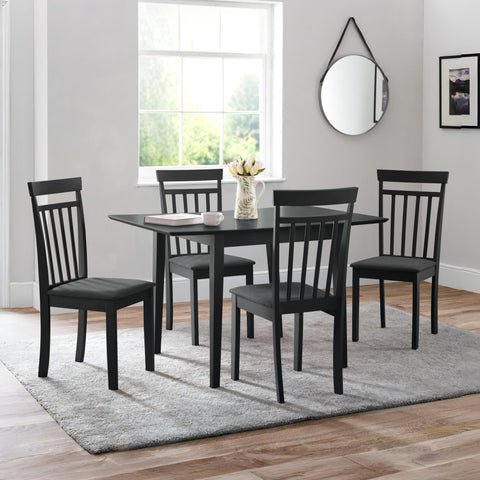 Square black dining table with four black wooden chairs with dark grey cushions on grey rug in room