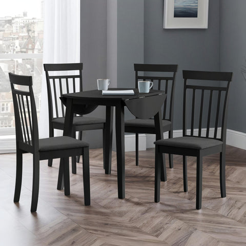 Black dining table with drop leaf and four black wooden chairs with dark grey cushions in room