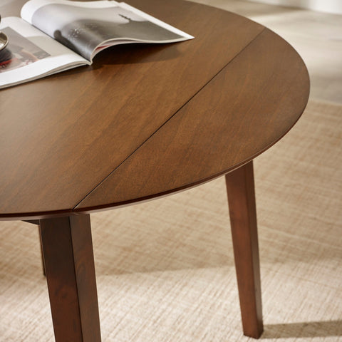 Close-up showing tabletop corners and seam lines on brown wooden round table with drop leaf folded down