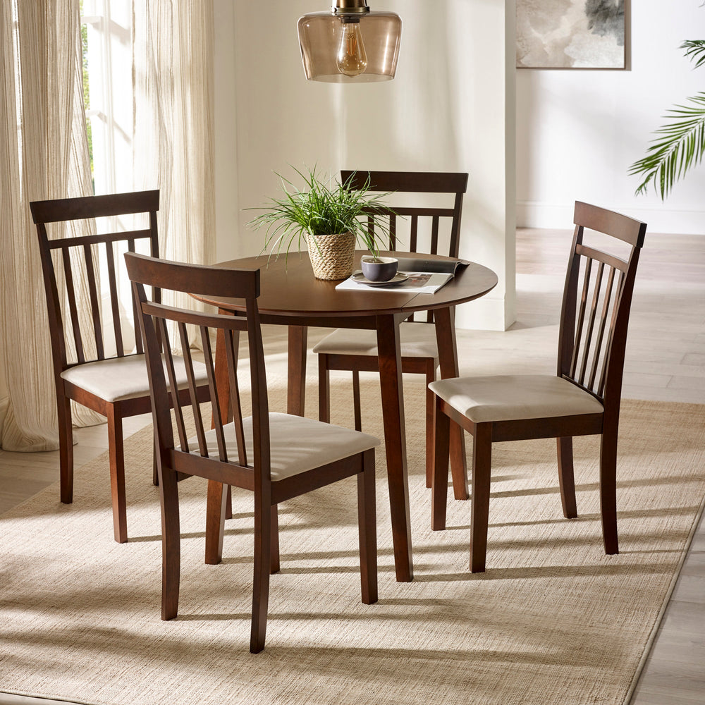 Two dark wood chairs with beige cushions with round dark wood dining table under glass pendant in bright room