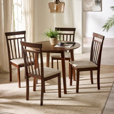 Two dark wood chairs with beige cushions with round dark wood dining table under glass pendant in bright room