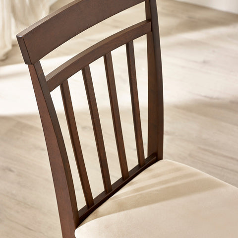 Close-up of dark wood dining chair back with vertical slats and beige cushioned seat on light floor