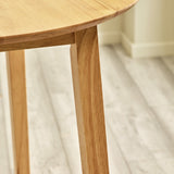 Close-up of smooth angled wood table leg on light-colored wooden floor