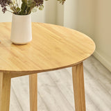 Close-up of round natural wood table top with white vase showing wood grain detail