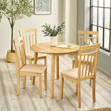 Four light wood dining chairs with beige padded seats around round table in a bright room with window and plant