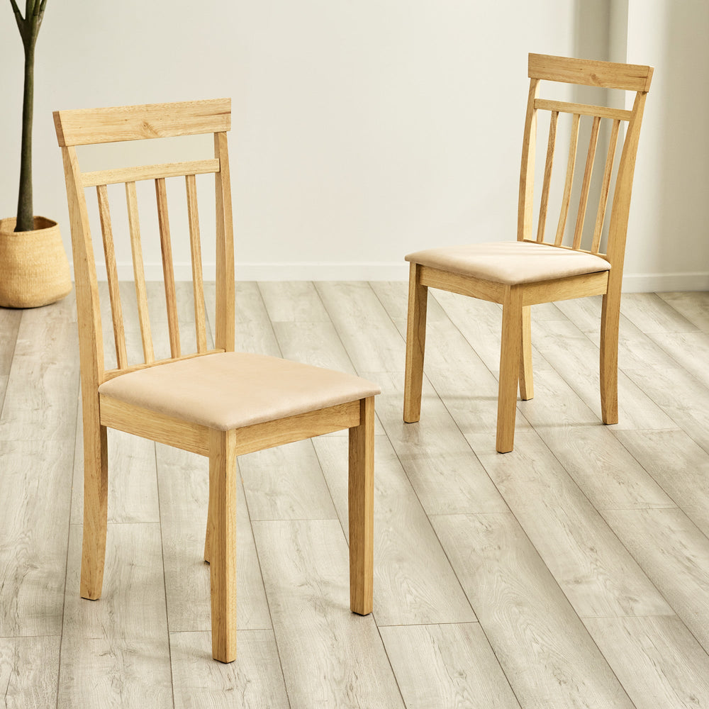 Two light wood dining chairs with beige cushions positioned on gray wood floor in bright room