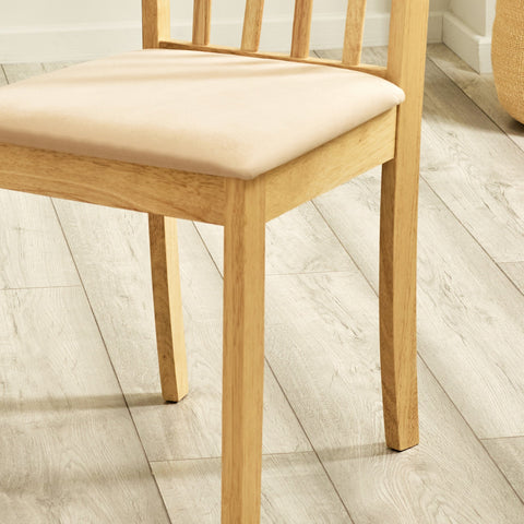 Close-up detail of wooden legs and lower frame of dining chair with beige cushioned seat on wood floor