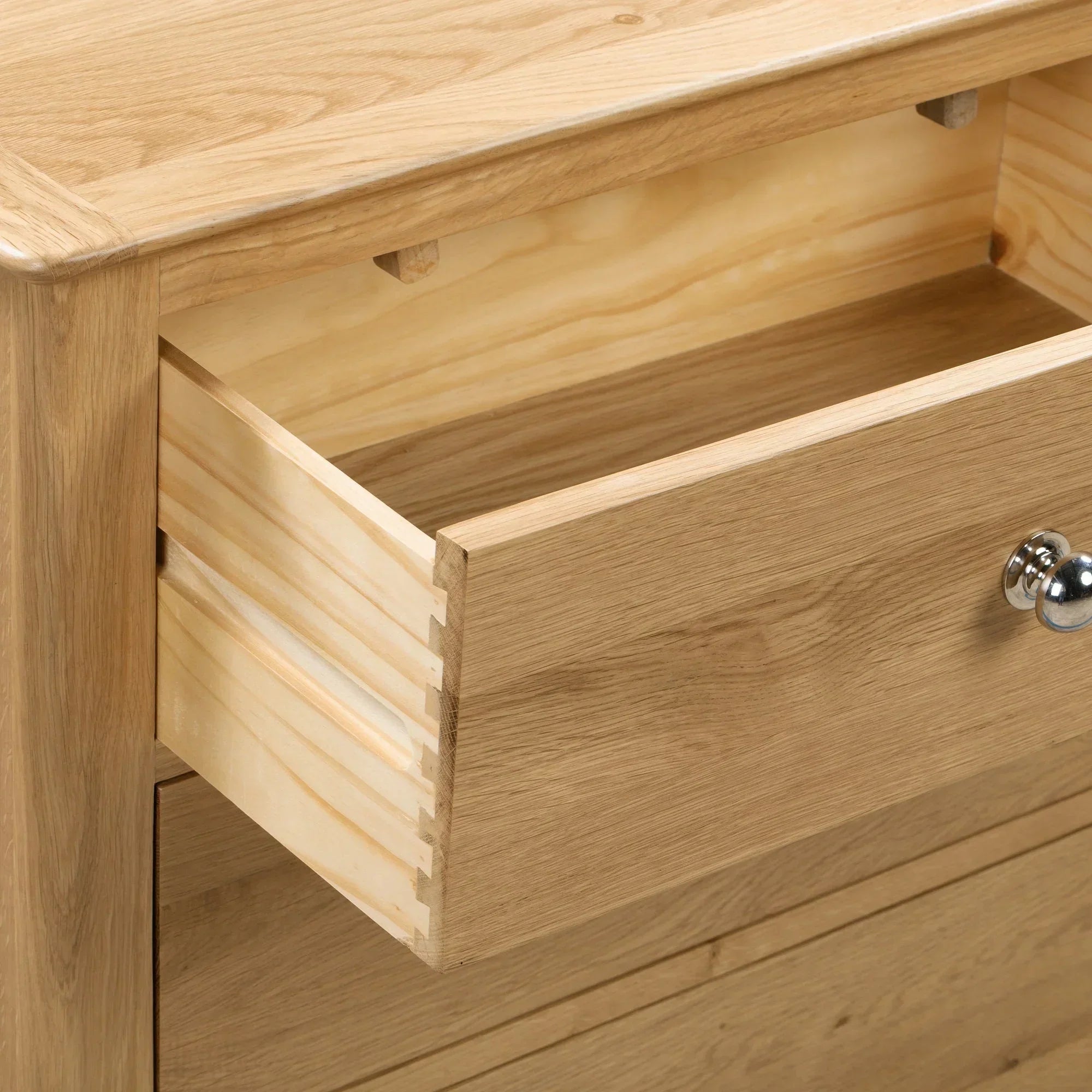 Detail of oak chest of drawers showing dovetail joints and metal handle on open drawer