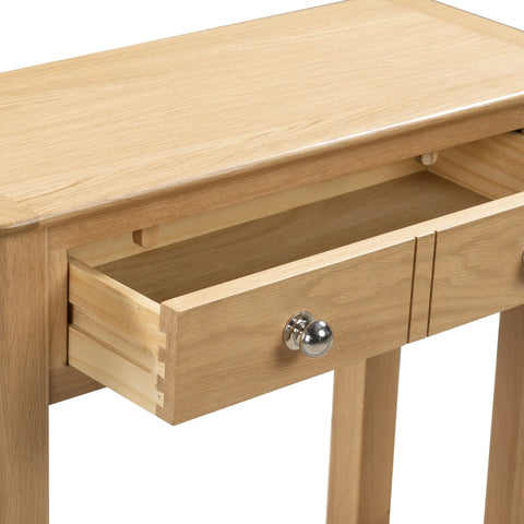 Oak console table close-up showing open drawer with silver knob and wood grain finish