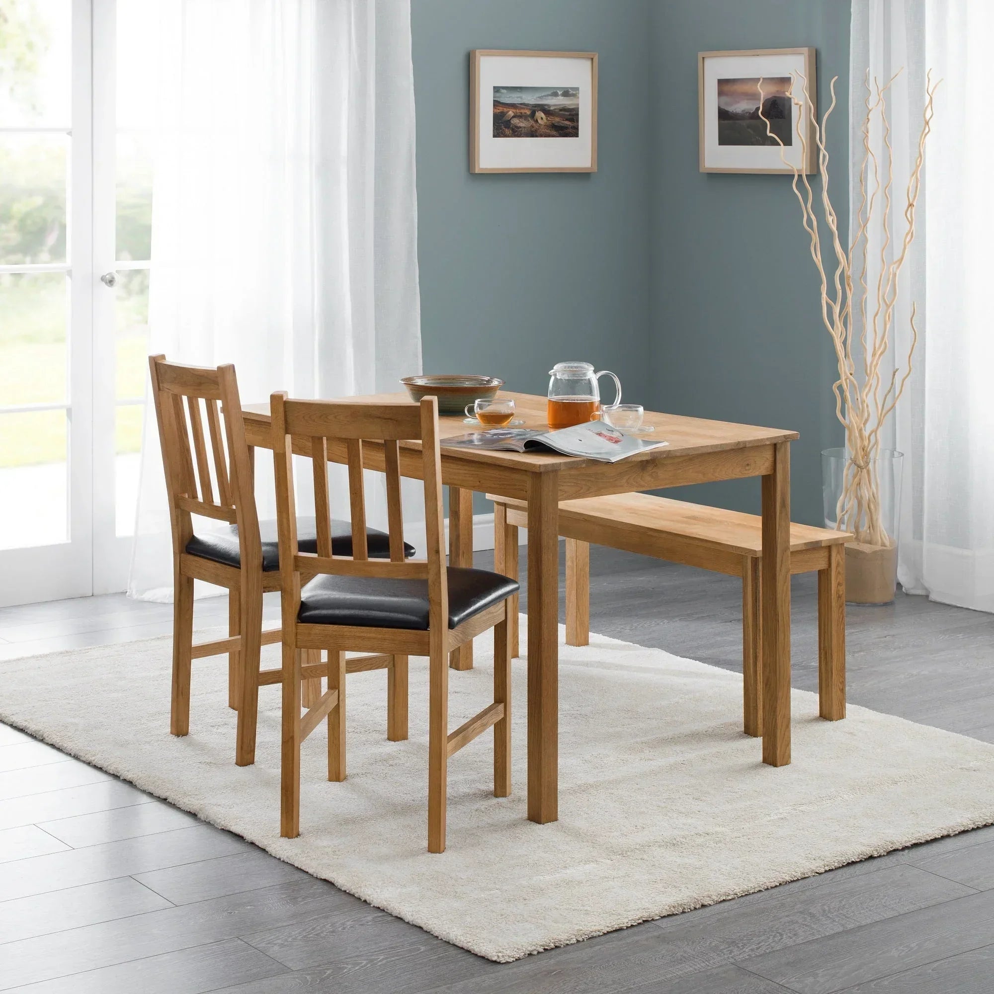 Oak rectangular dining table with two chairs and bench on cream rug in modern dining room