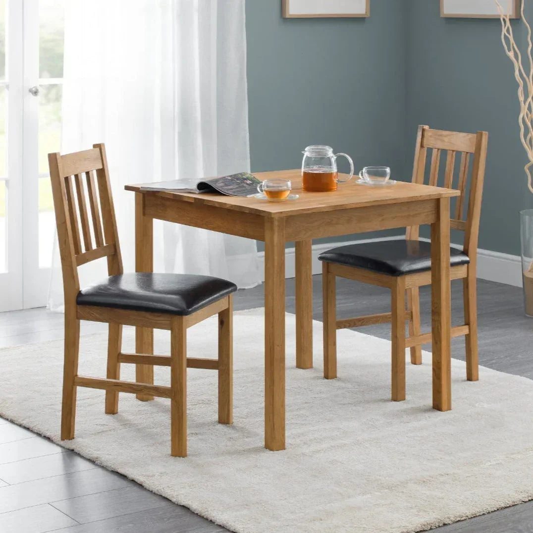 Oak square dining table with two wooden chairs and black seats on a cream rug