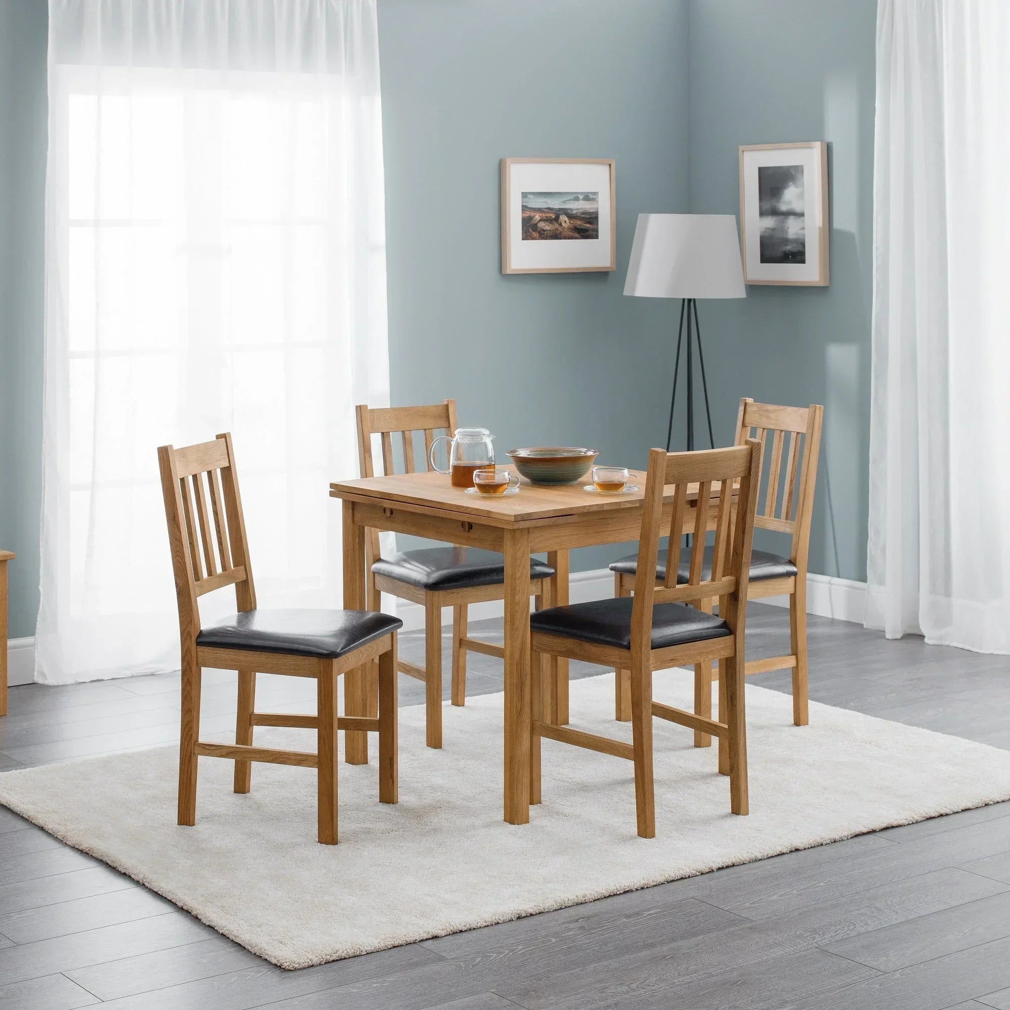 Oak extending dining table with four chairs on cream rug in airy dining room